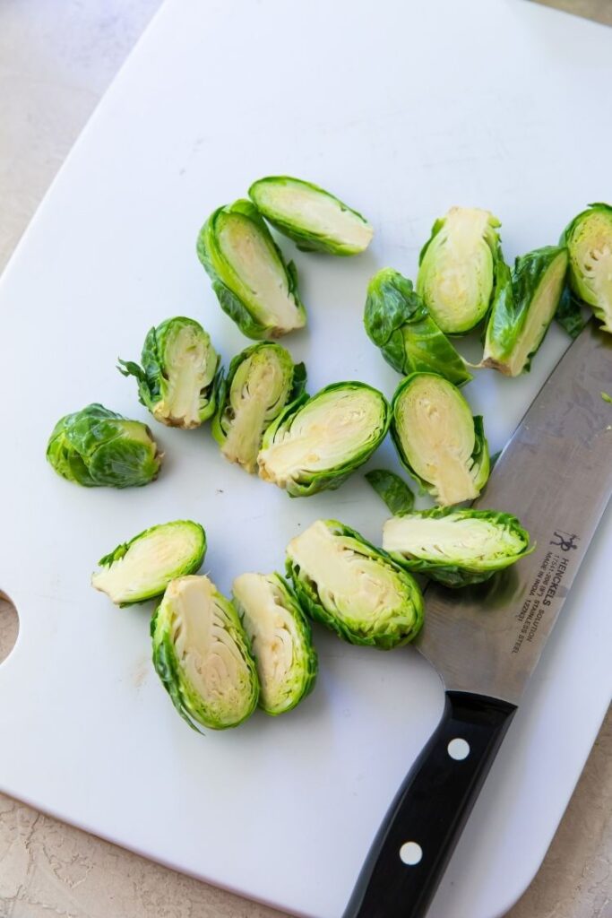 brussel sprouts cutting half on a white cutting board