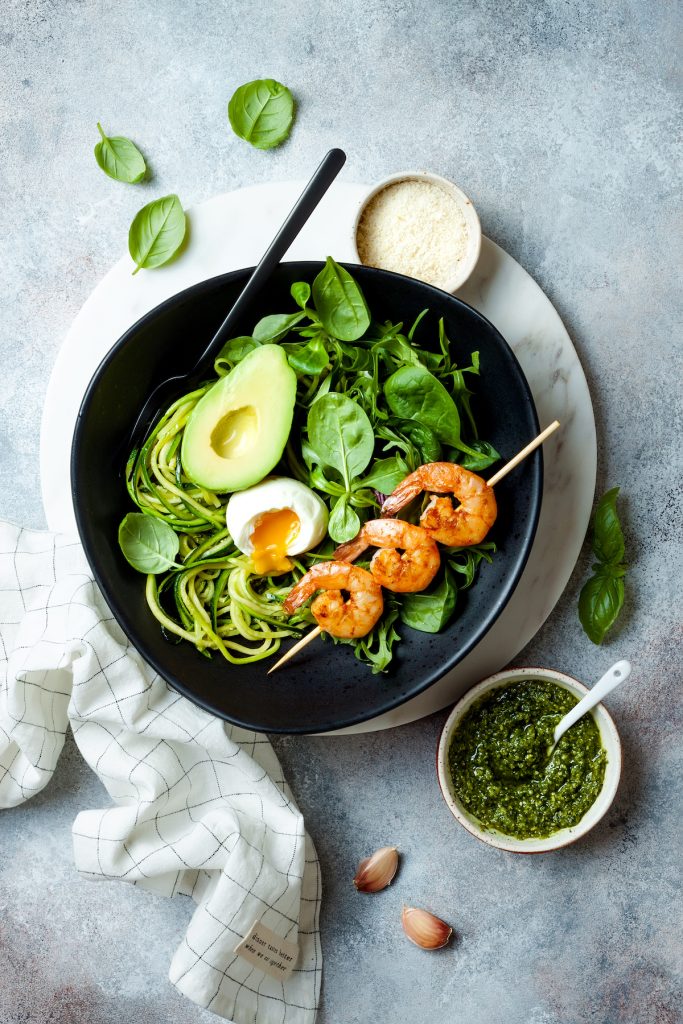 shrimp, noodles, avocado and spinach in a cast iron skillet