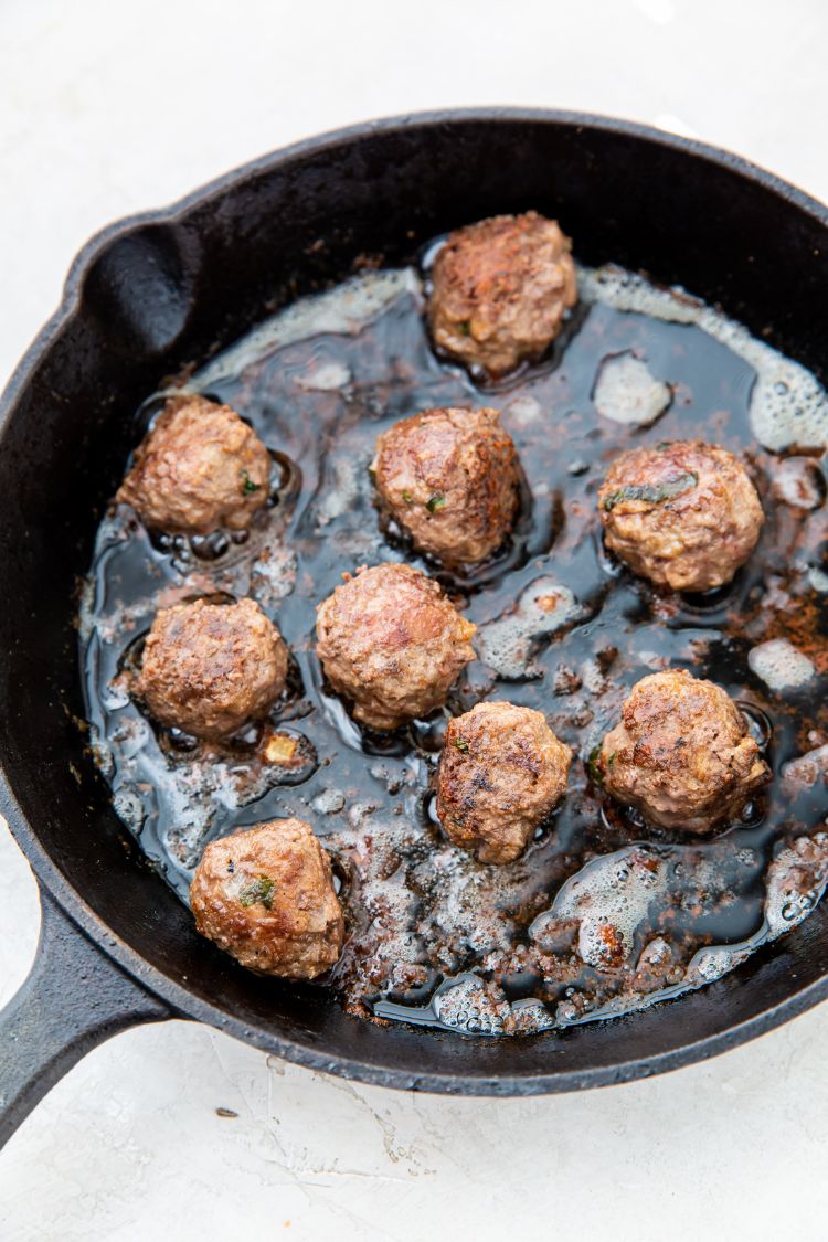 keto meatballs being cooked in a cast iron skillet
