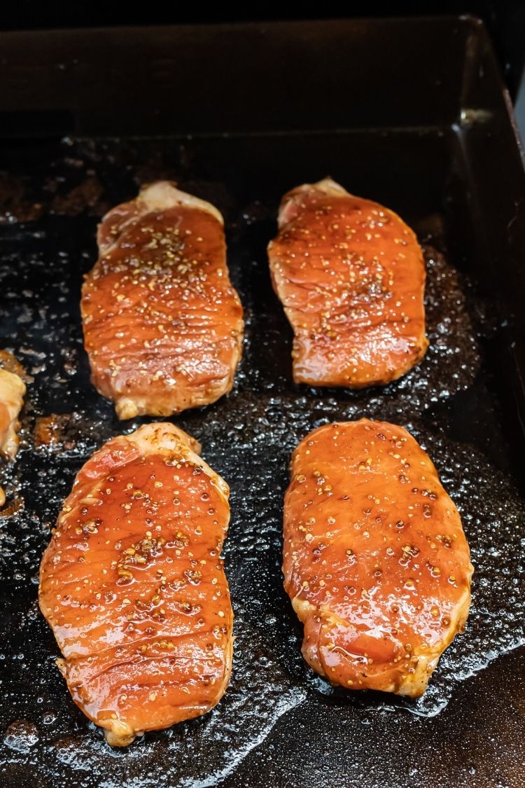 raw pork chops being cooked on a Blackstone Griddle