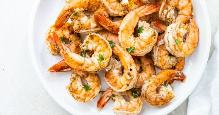 Grilled shrimp topped with parsley, garlic and lemon juice on a white plate