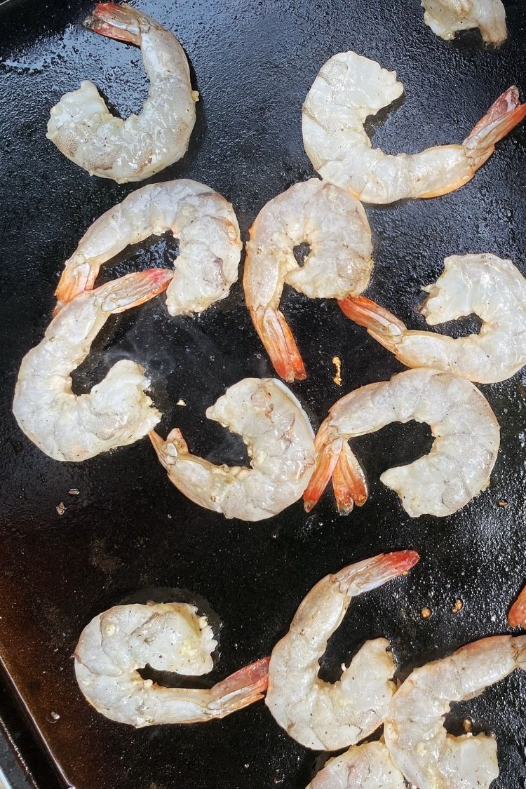 raw shrimp being cooked on a blackstone