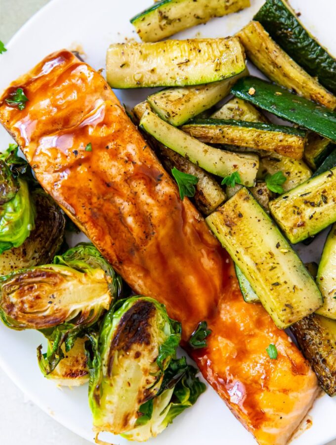 grilled teriyaki salmon with grilled zucchini and Brussel sprouts on a white plate