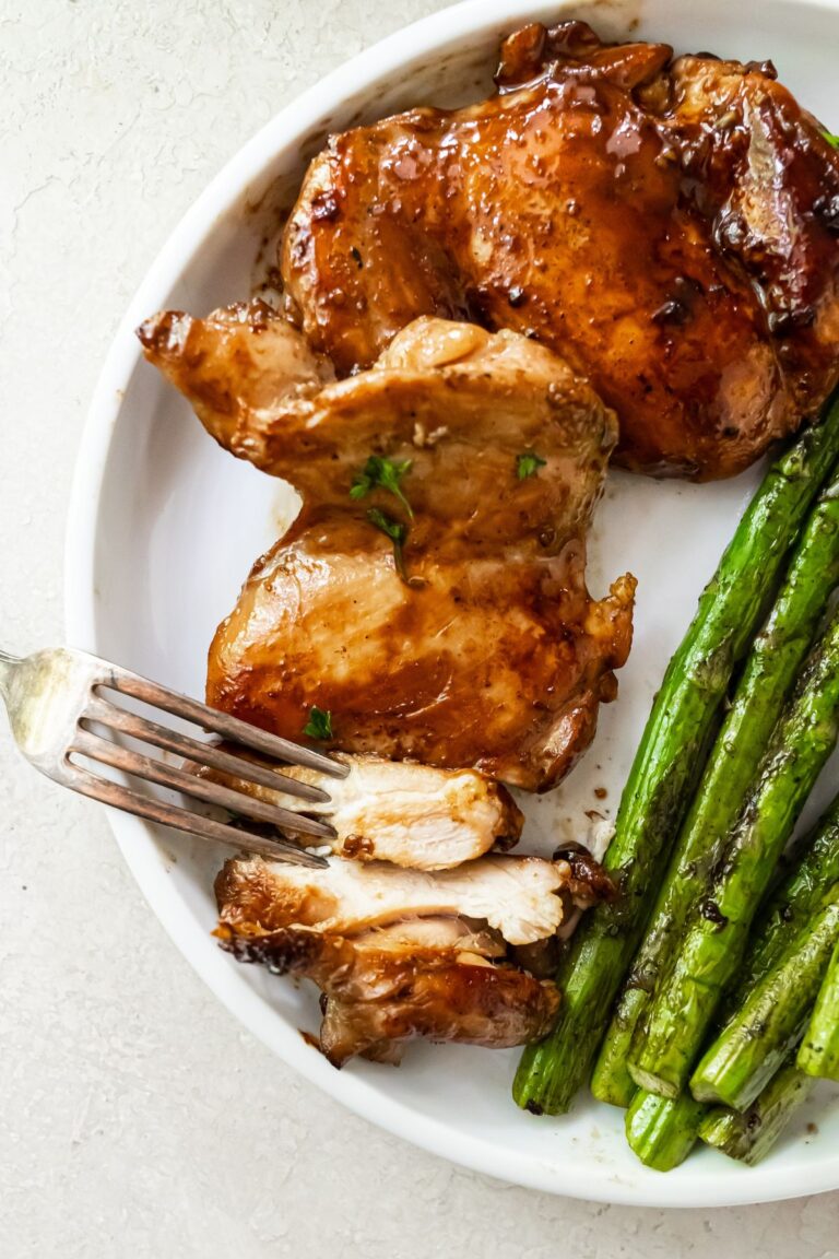 Teriyaki Chicken with asparagus on a white plate with a fork.
