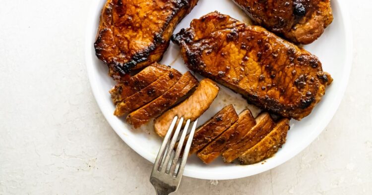 Grilled pork chops on a white plate with a fork