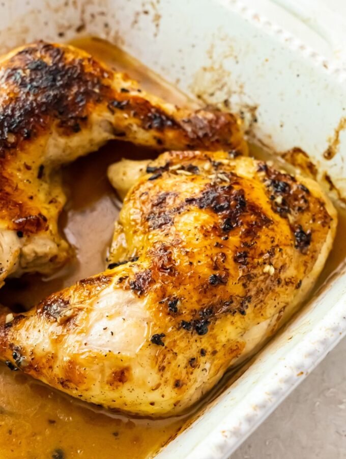 broiled chicken quarters in a white baking dish