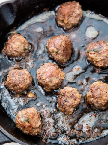 keto meatballs being cooked in a cast iron skillet