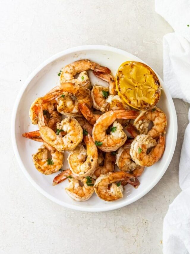 blackstone Grilled shrimp topped with parsley, garlic and lemon juice on a white plate with a white napkin