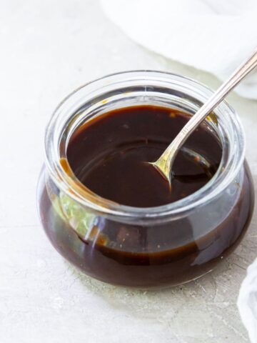 honey paleo teriyaki in a glass container with a spoon on a light background