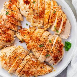 4 cooked and sliced 4 oz chicken breasts on a white plate