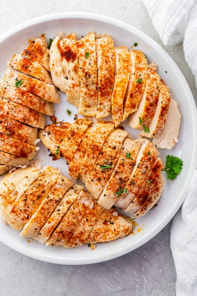 4 cooked and sliced 4 oz chicken breasts on a white plate