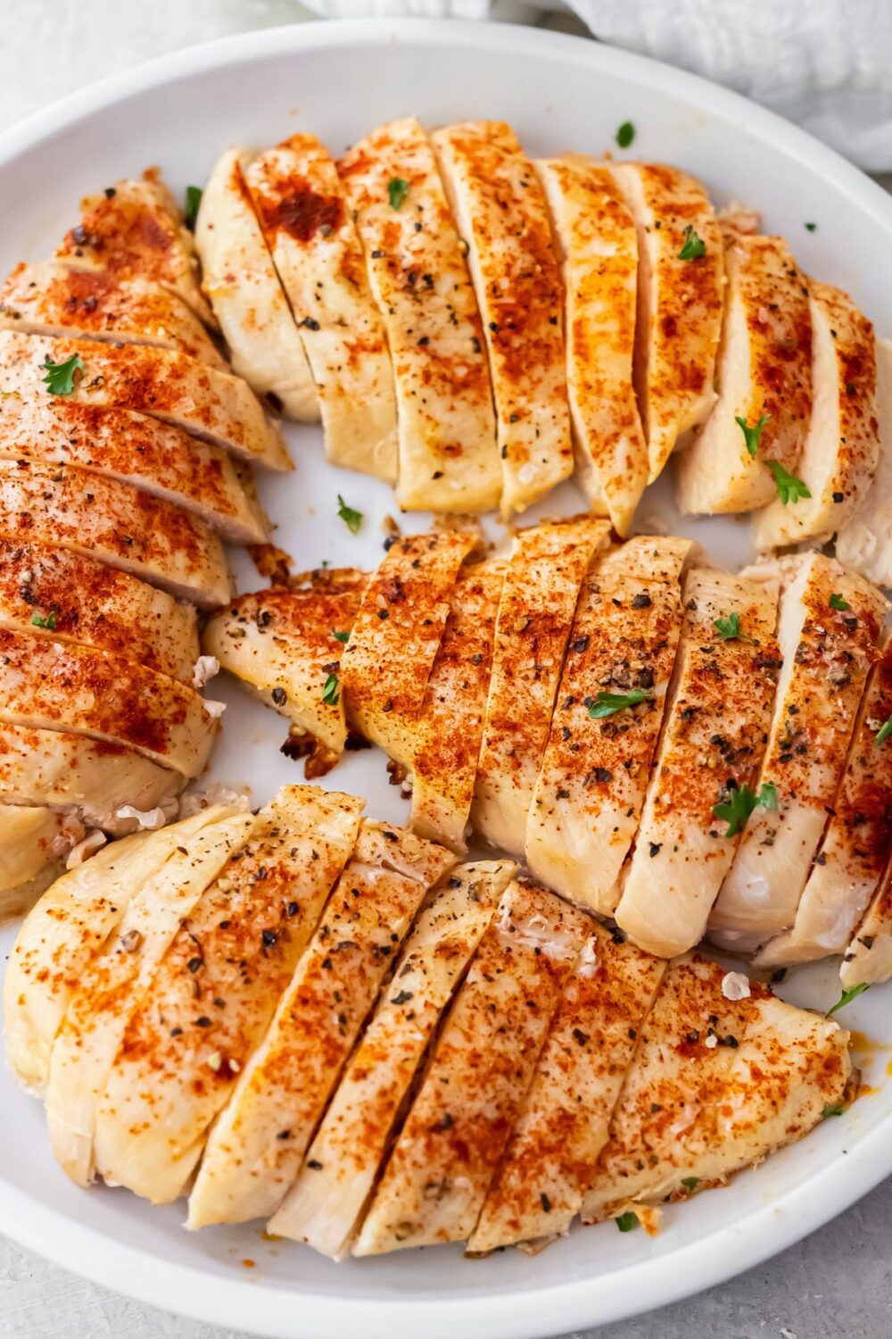 4 cooked and sliced 4 oz chicken breasts on a white plate