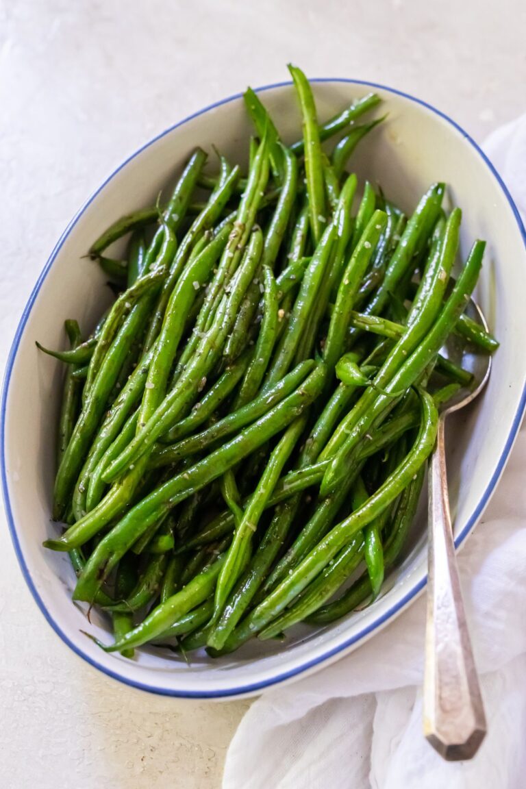 Blackstone Green Beans with pepper and salt in a white bowl with a spoon.
