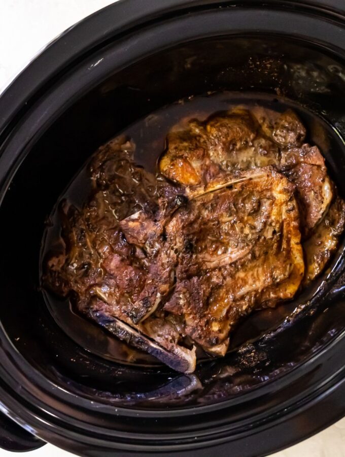 pork chops in a black crockpot after being cooked