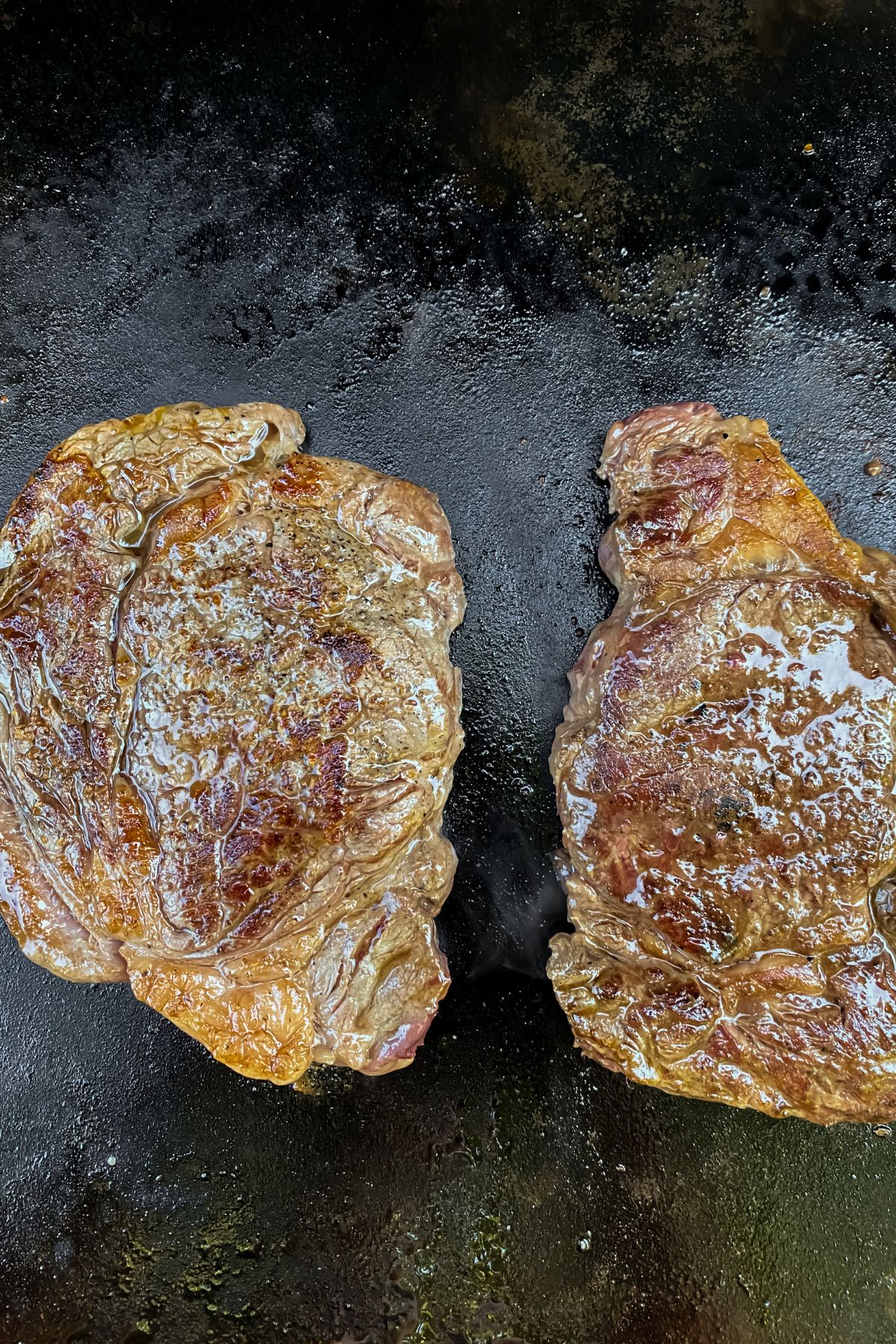 two cooked ribeye steaks on a Blackstone Griddle right before being removed.