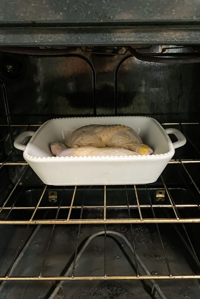 chicken leg quarters being cooked in a white baking dish under the broiler