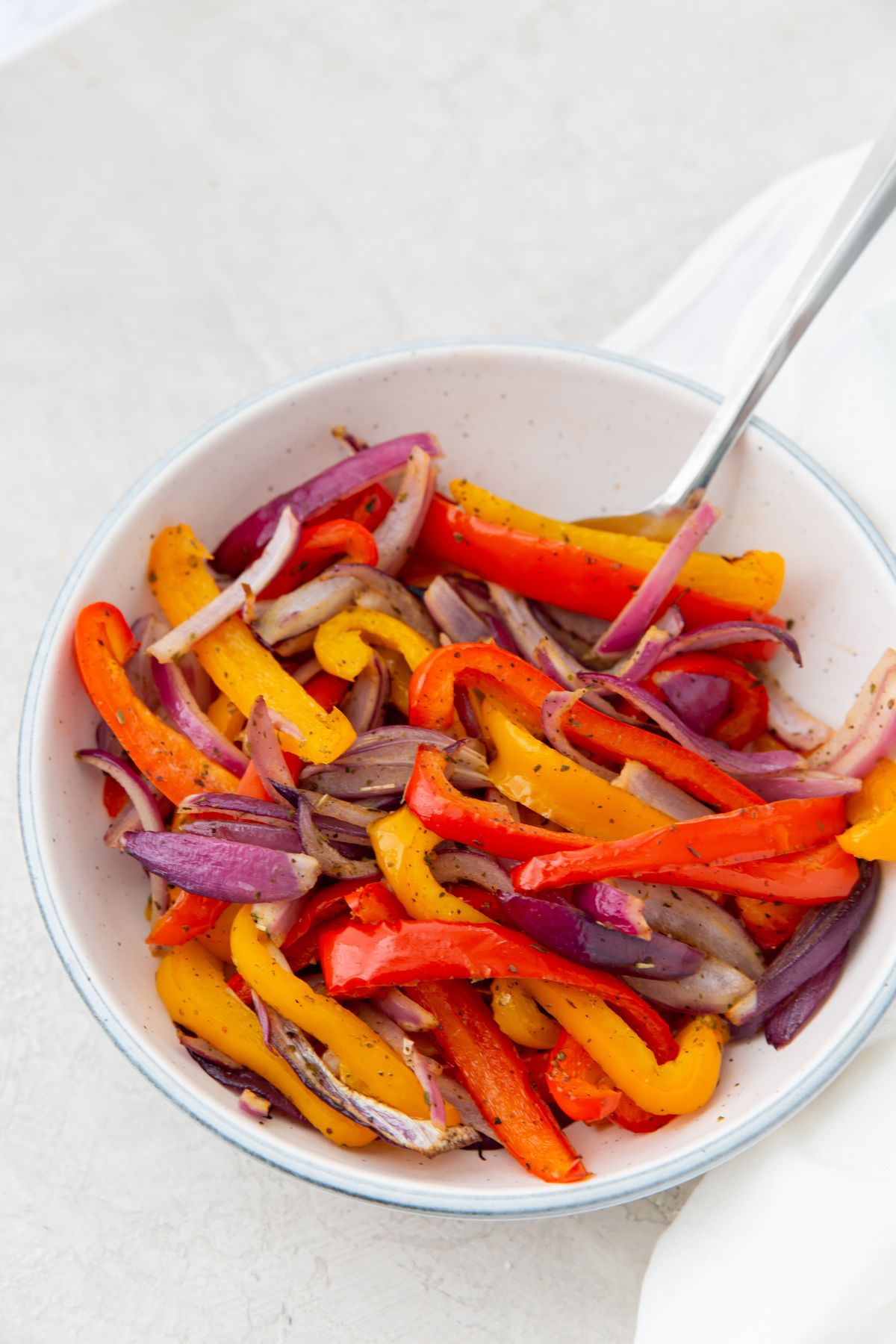 cooked peppers and onions in a white bowl with a spoon