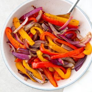 cooked peppers and onions in a white bowl with a spoon