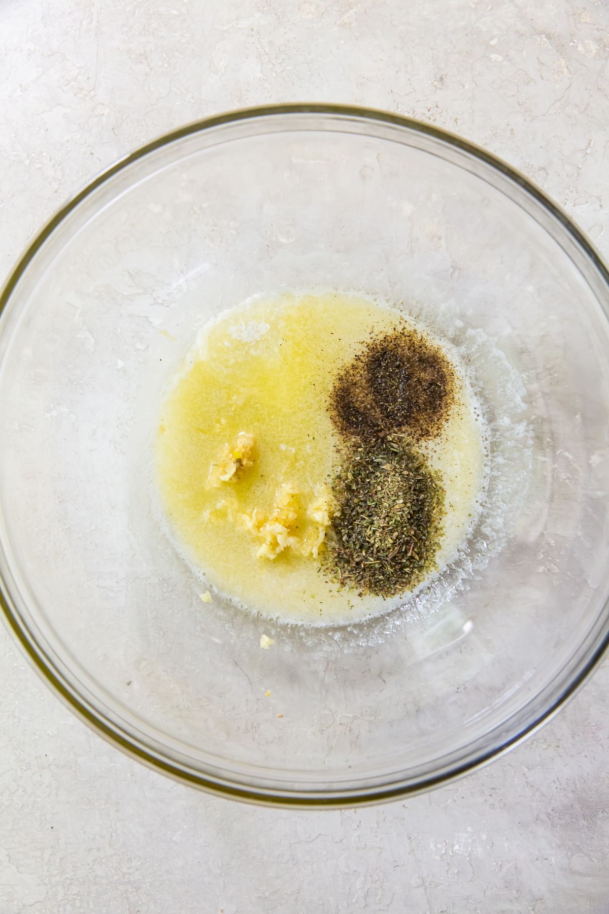 Melted butter and spices in a glass bowl on a white tabletop