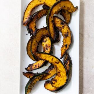 Grilled acorn squash on a white rectangular plate