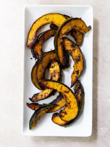Grilled acorn squash on a white rectangular plate