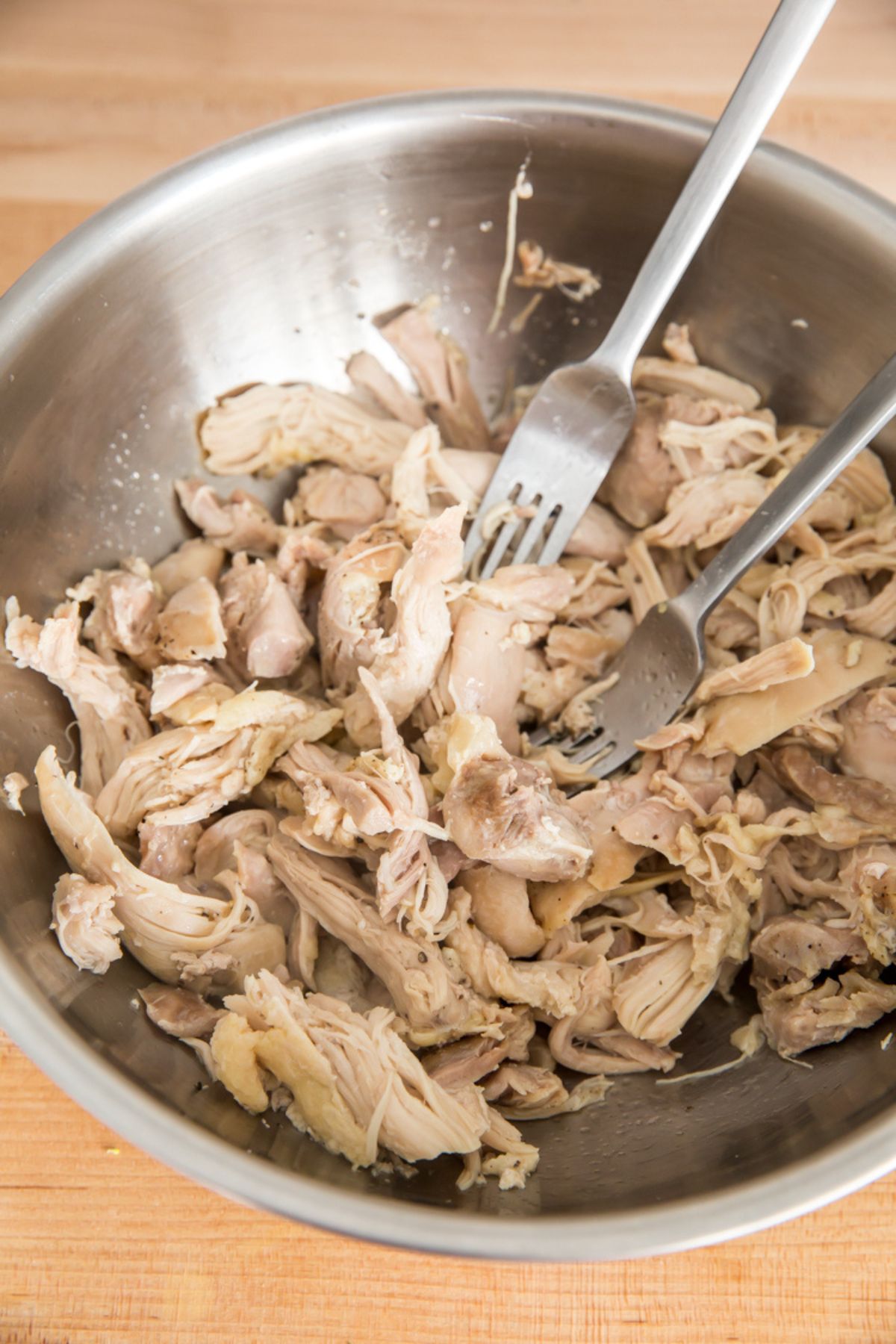 shredded chicken thighs in a metal bowl