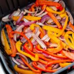 peppers and onions cooked and in an air fryer basket