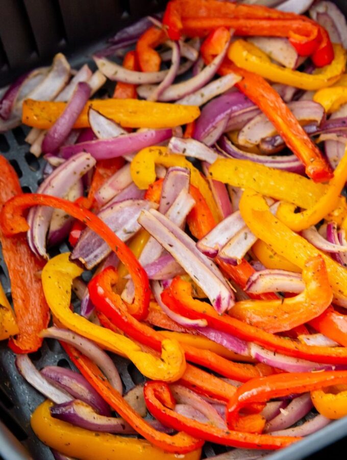 peppers and onions cooked and in an air fryer basket
