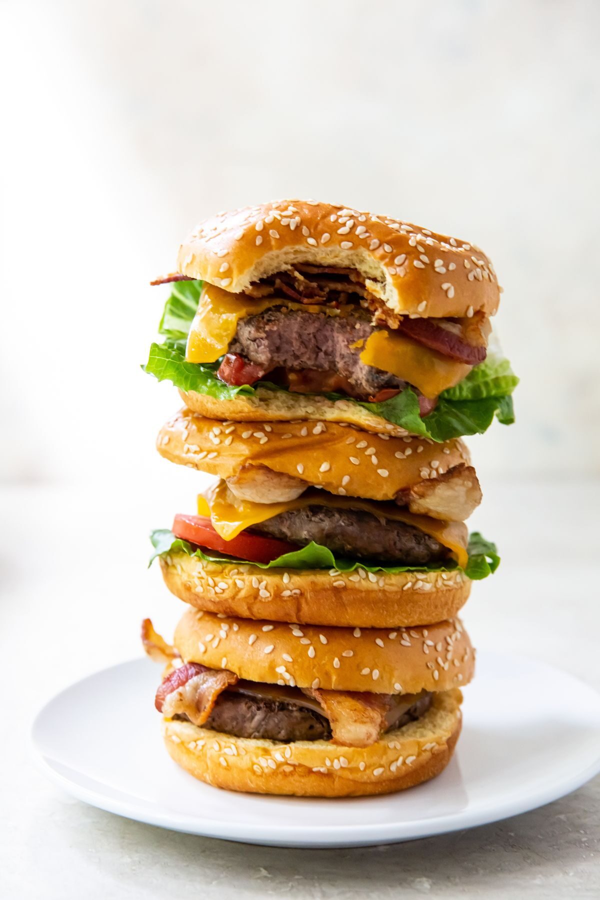 three burgers stacked together. top burger has a bite taken out of it.