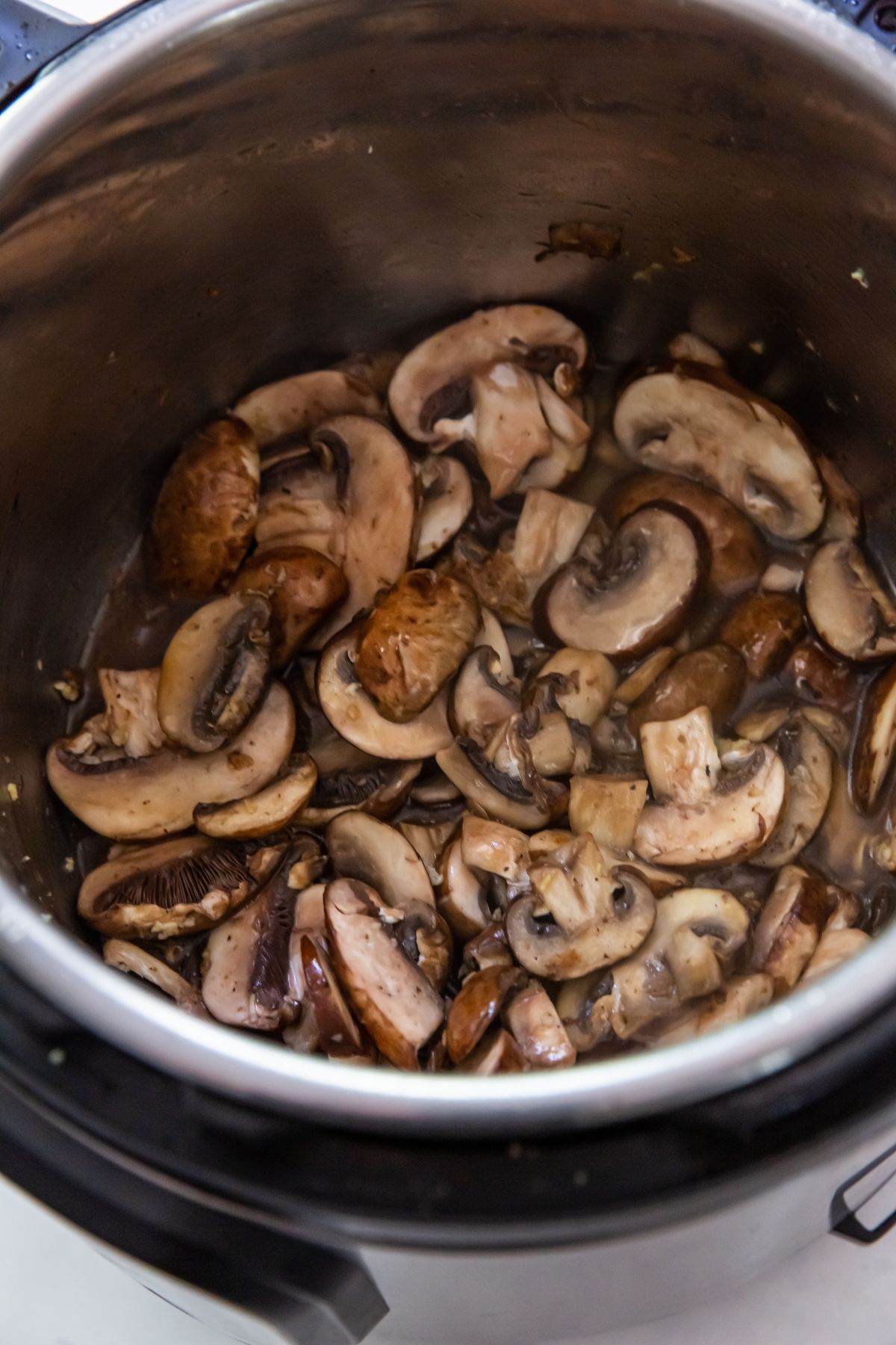 cooked mushrooms inside the instant pot with chicken broth inside