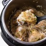 instant pot chicken thighs with rice with a spoon lifting a chicken thigh out of the instant pot