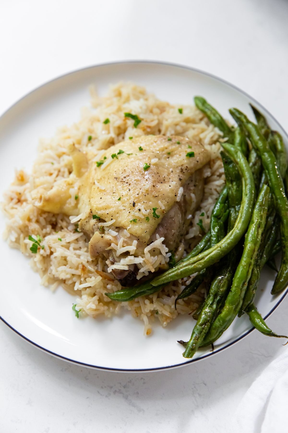 instant pot chicken thighs with rice and side of green beans on a white plate