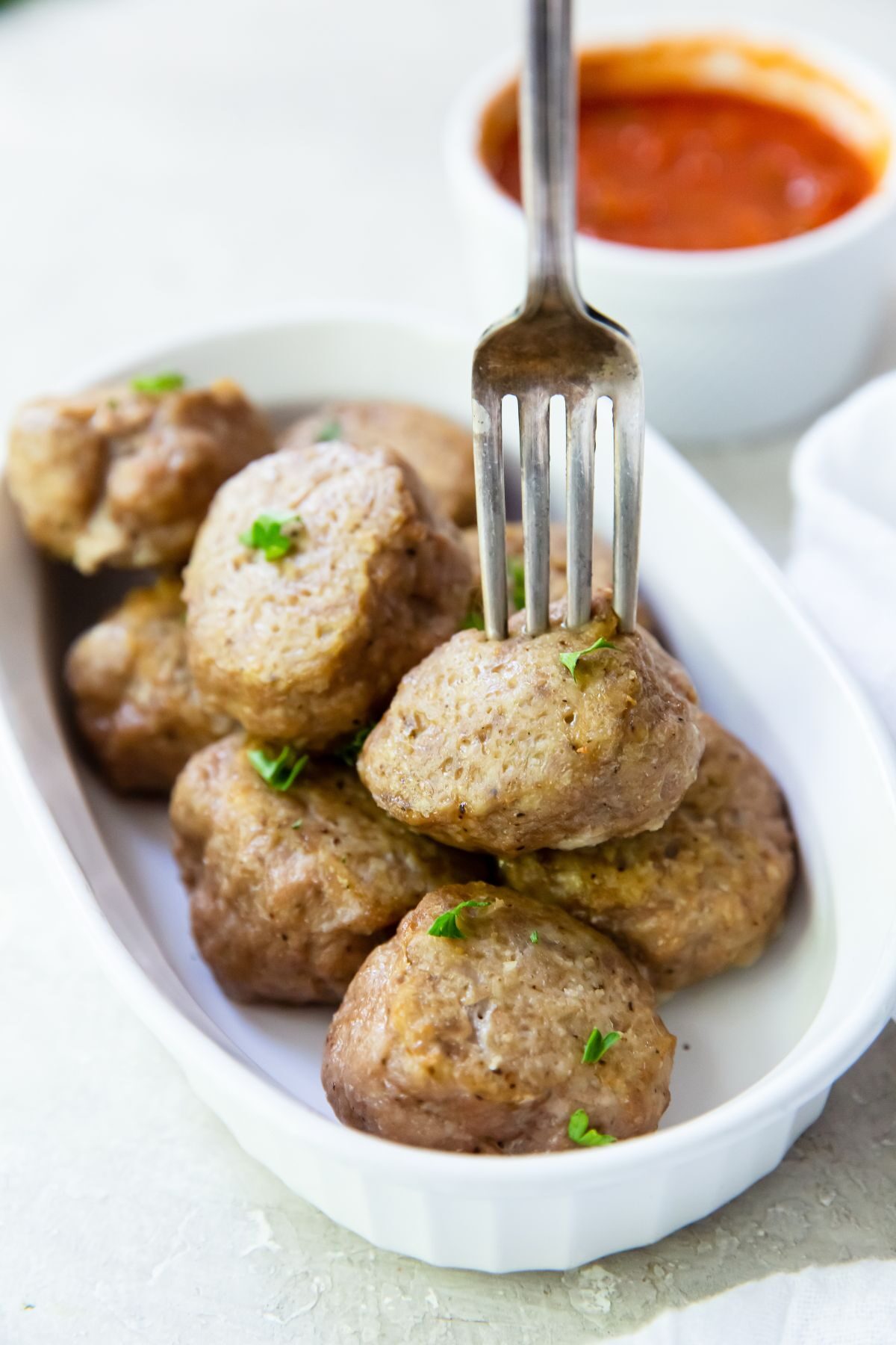 cooked oven turkey meatballs on a white casserole dish with a meatball on a fork