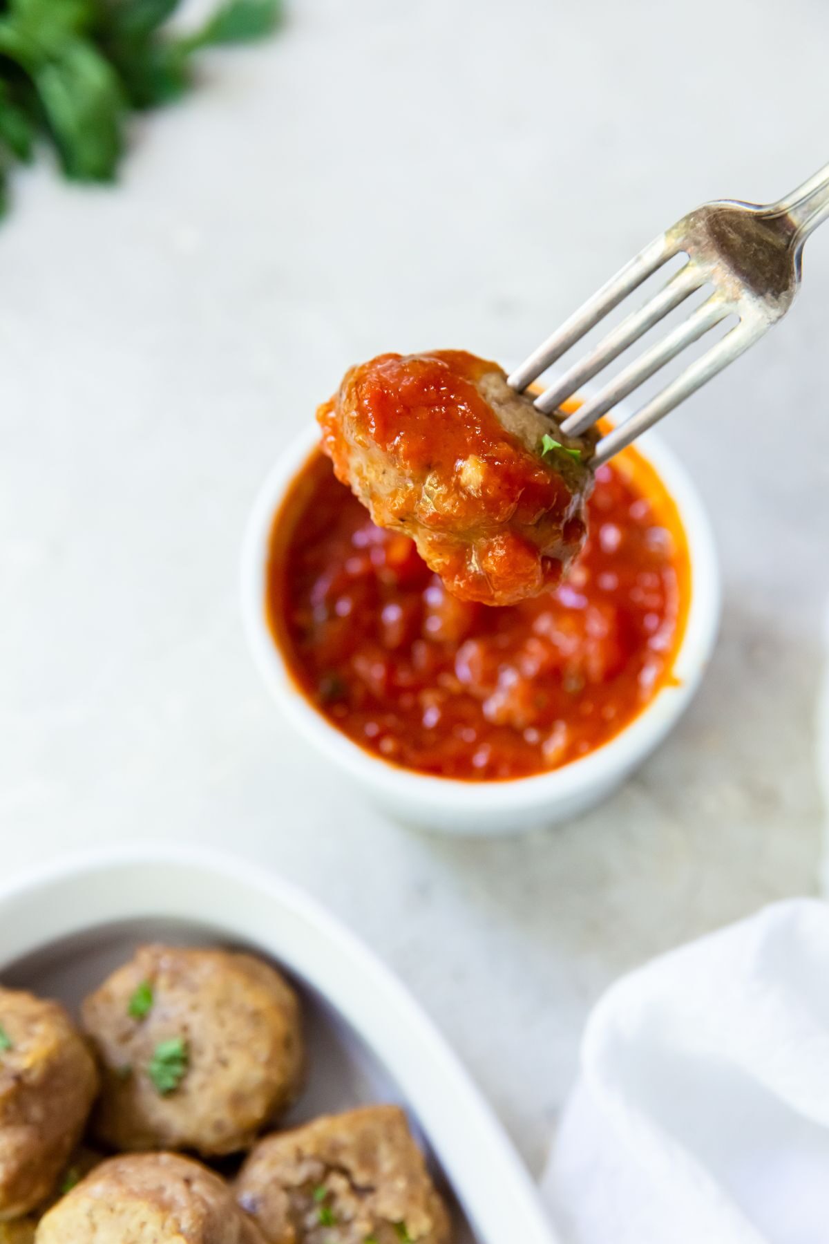 marinara in a white dish with a meatball on a fork