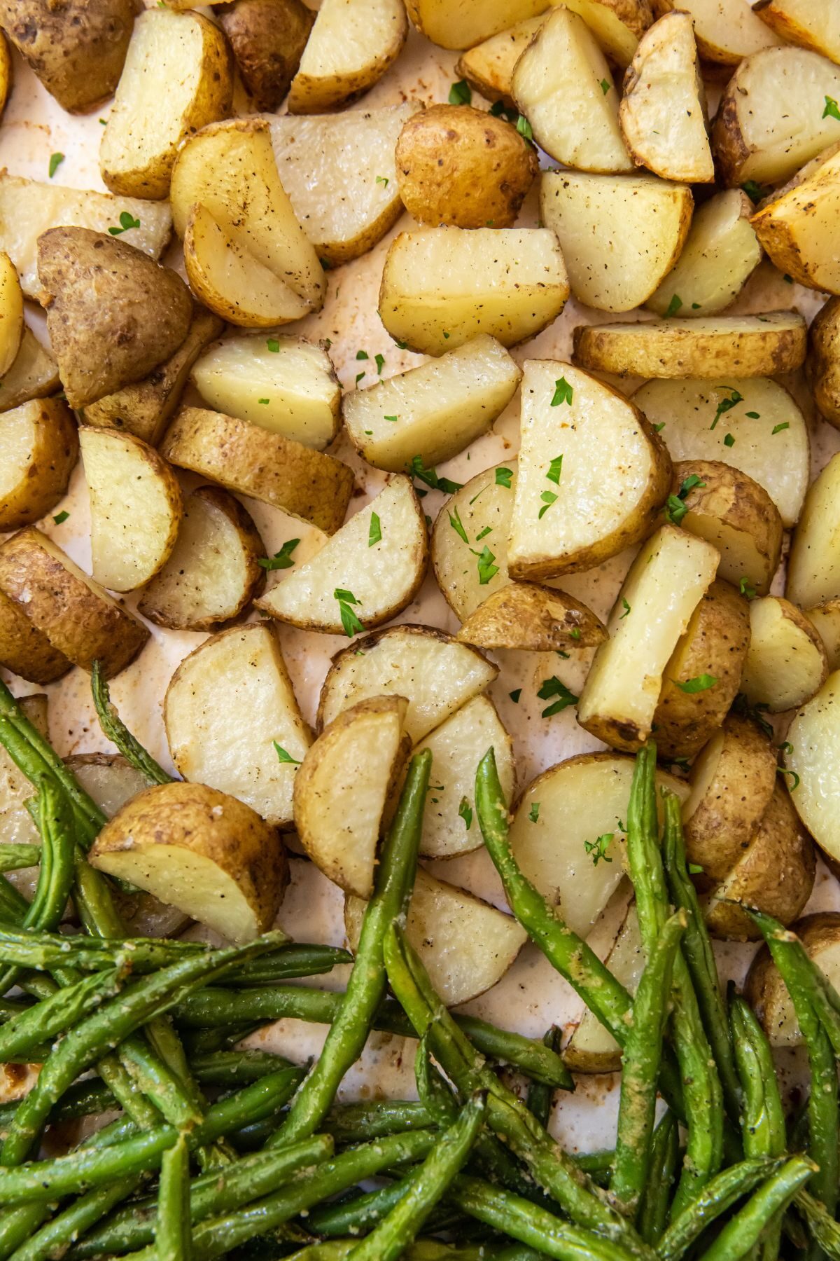 Cooking sheet with parchment paper with cooked potatoes and green beans on it