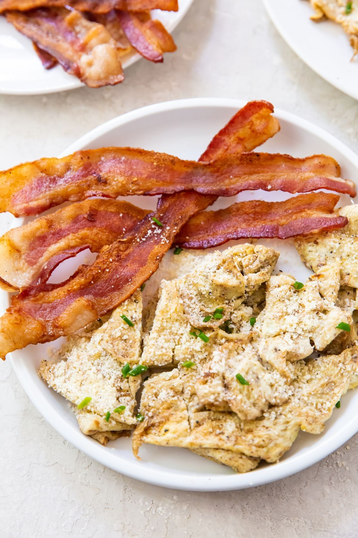 blackstone scrambled eggs on white plate with bacon