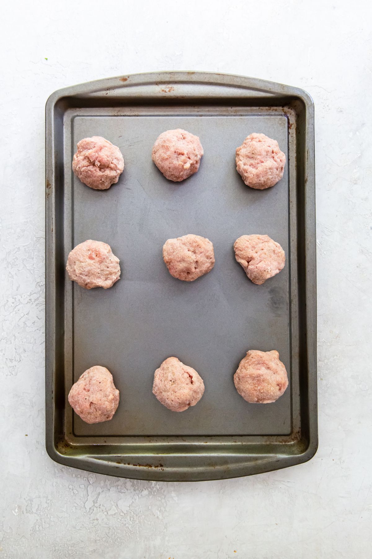 raw frozen meatballs on a sheet pan