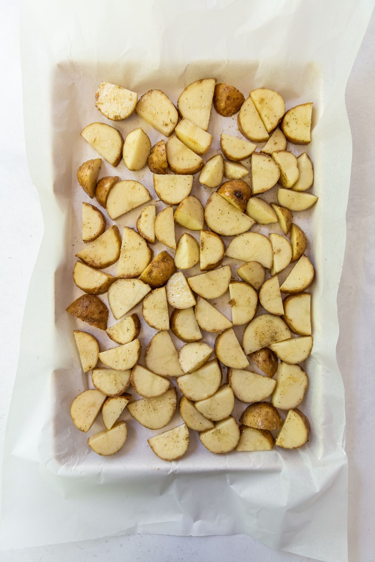 cooking sheet with parchment paper seasoned potatoes on top