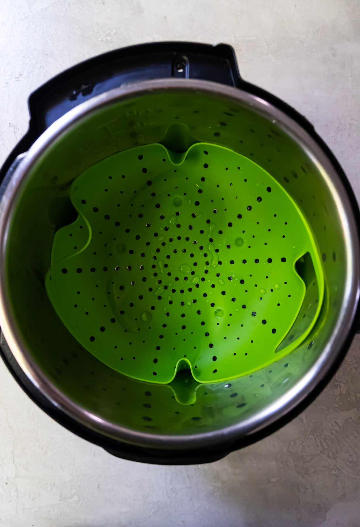A green mesh colander inside an instant pot.