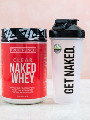 clear naked whey review. a container of clear naked whey and a plastic water bottle on a white surface