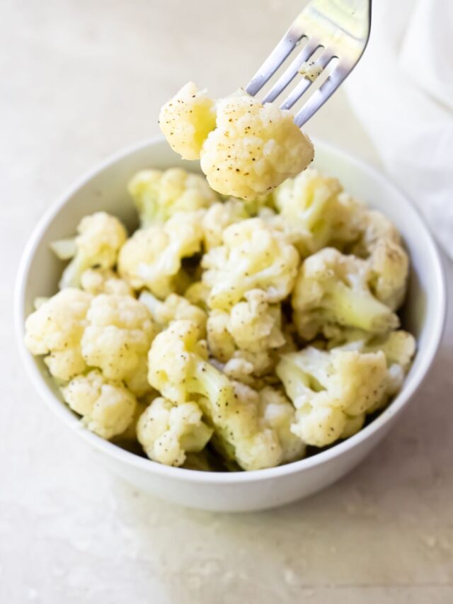 Cauliflower sitting in a ceramic bowl on a white countertop