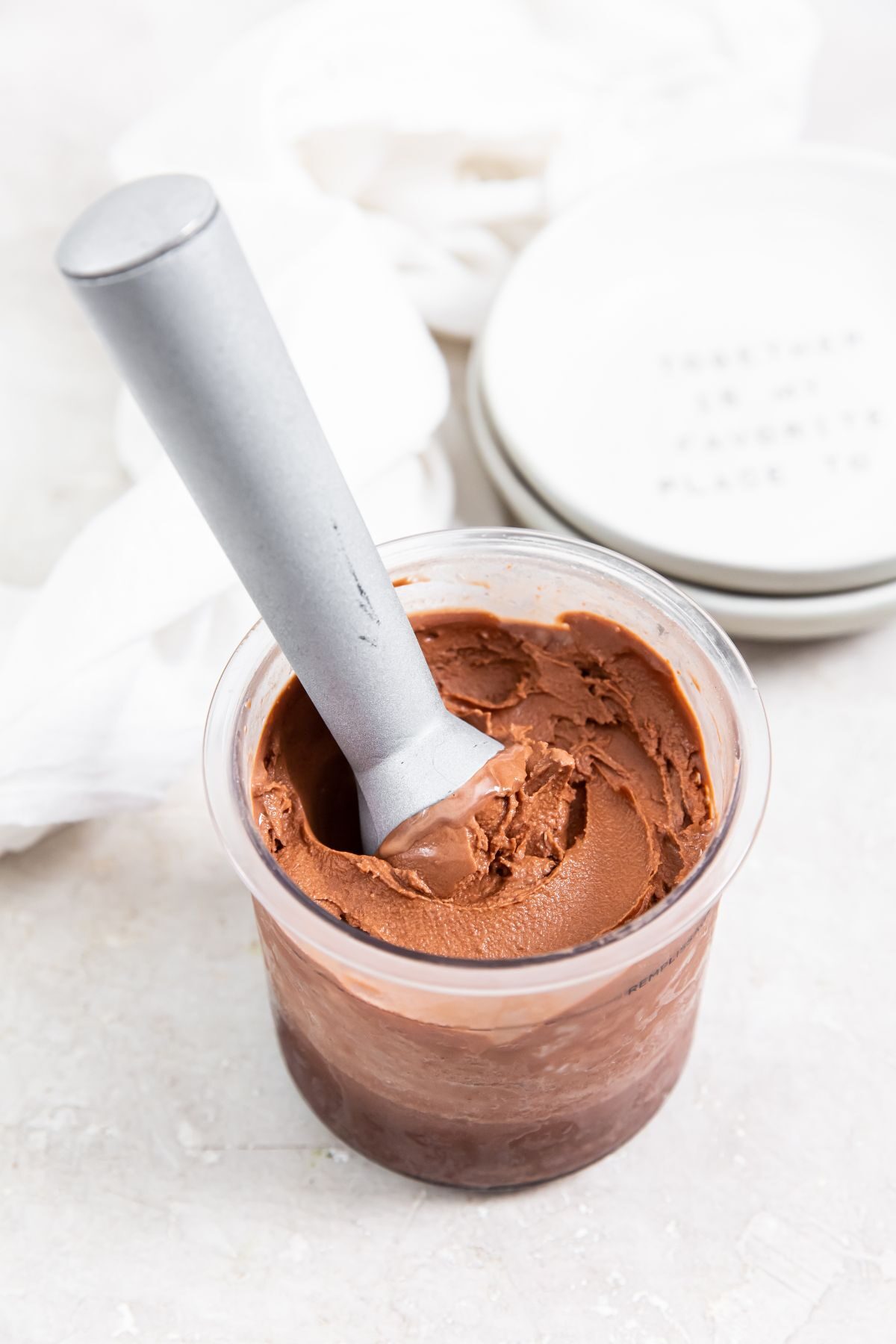 dairy free keto chocolate protein ice cream in a pint with an ice cream scoop and small white bowls