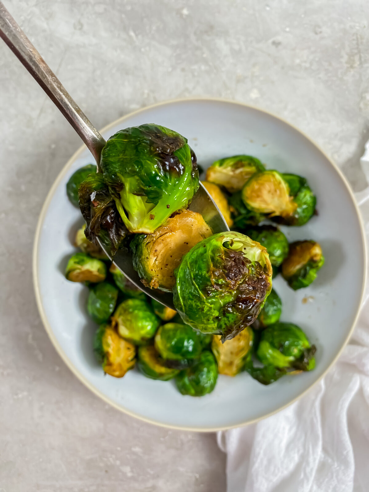 Air fried brussel sprouts on a spoon over a white bowl