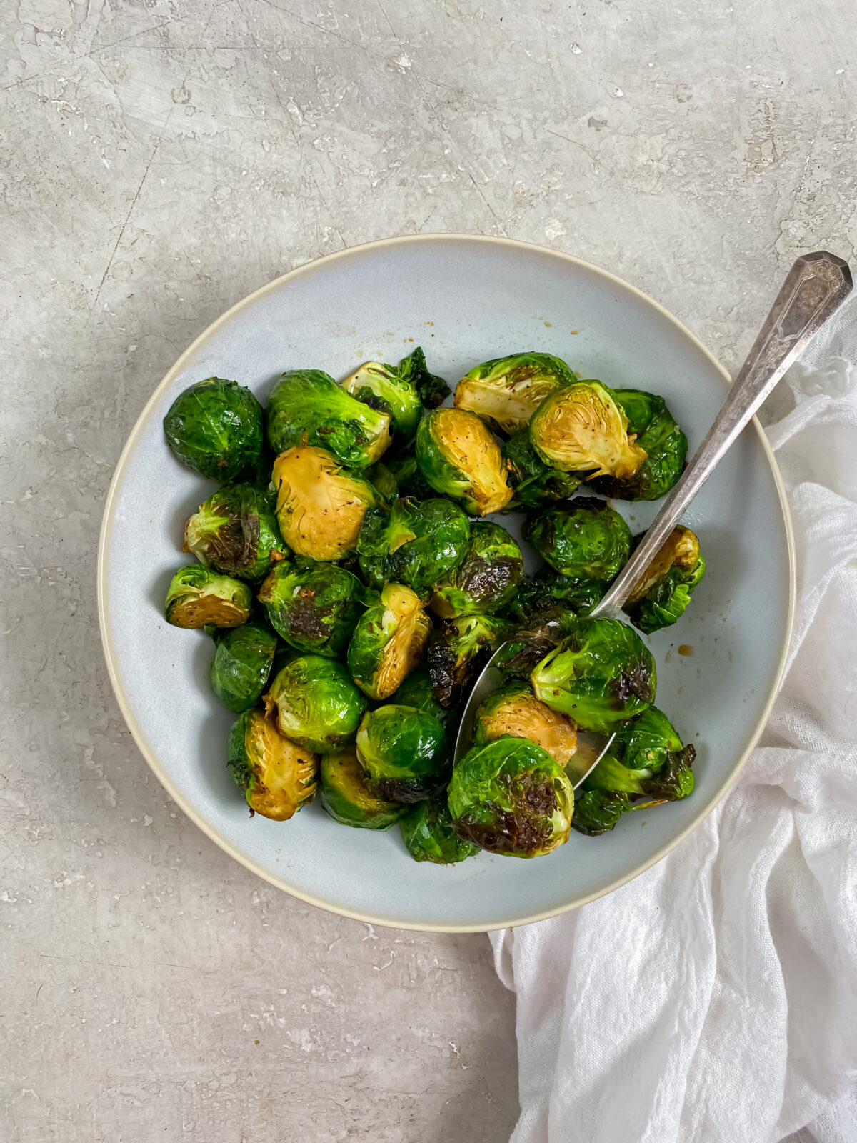 Brussel sprouts in a bowl with a spoon and white napkin 