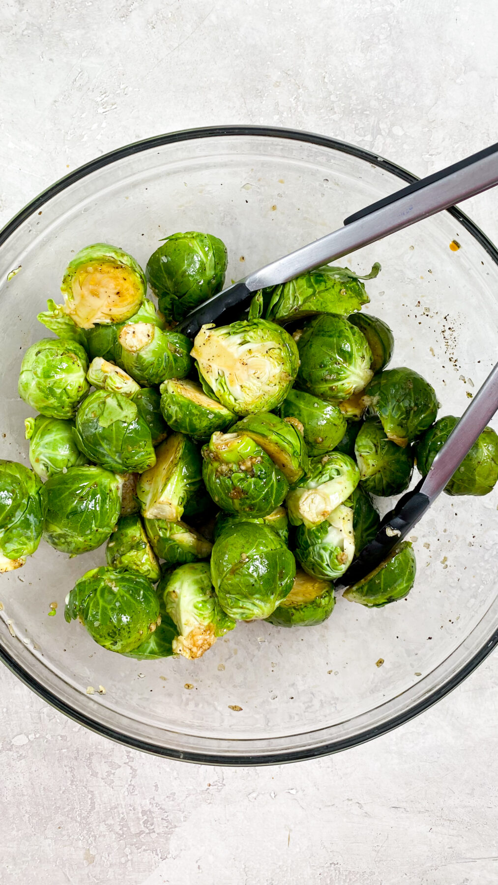 brussel spurts being tossed in a large bowl with seasonings