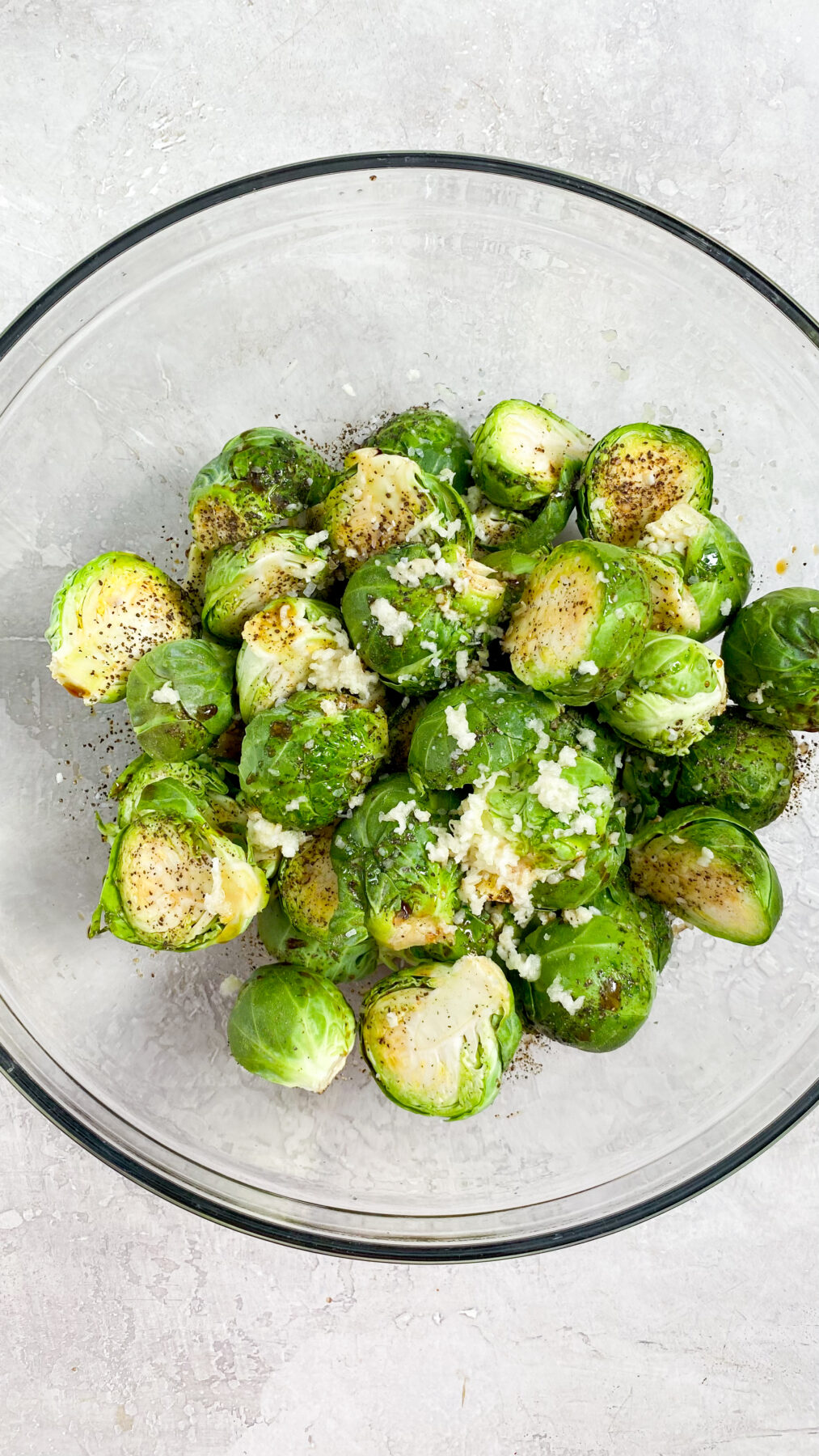 brussel sprouts with seasonings on top in a clear bowl