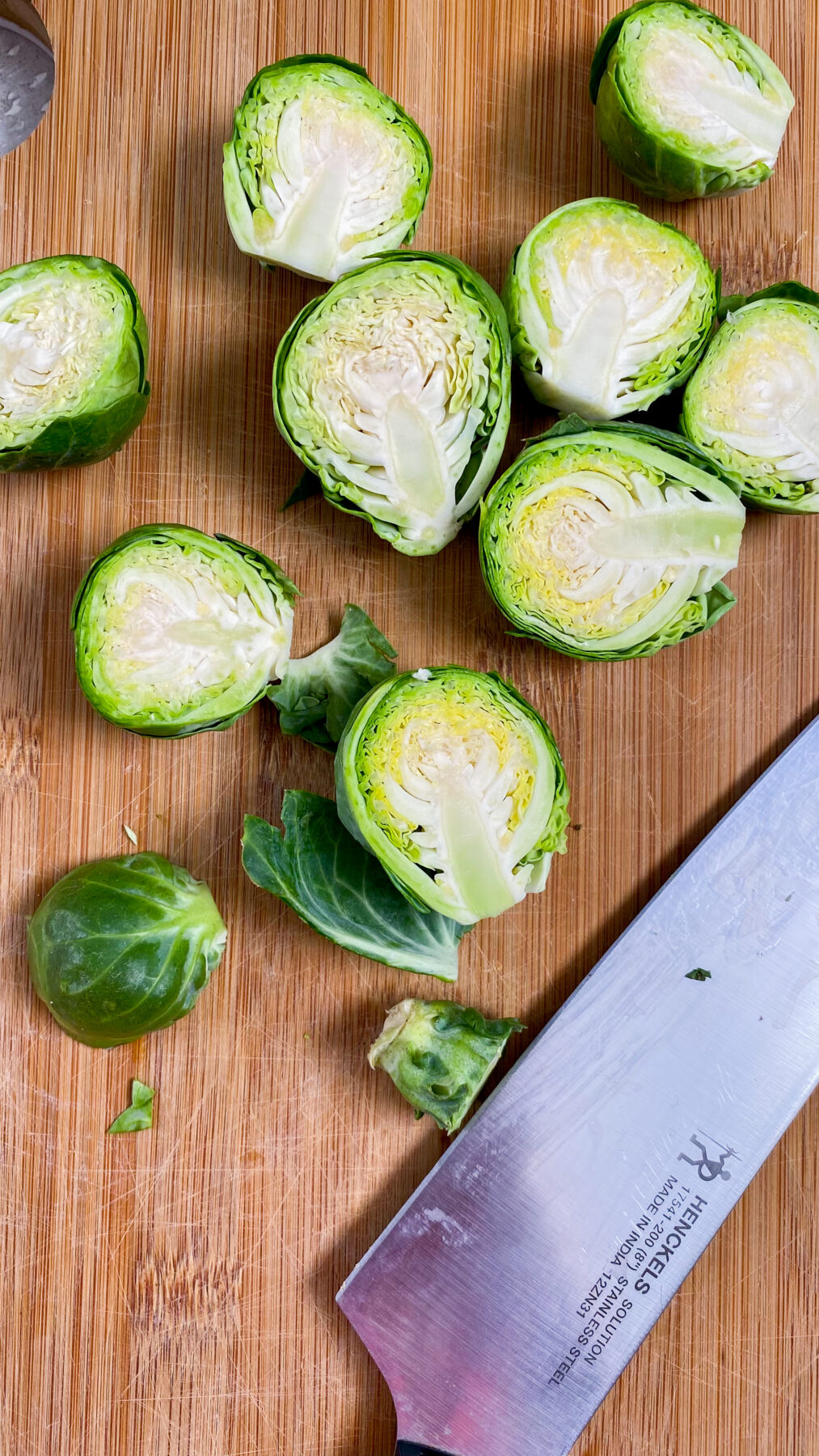 brussel sprouts being cut in half on a wooden cutting board
