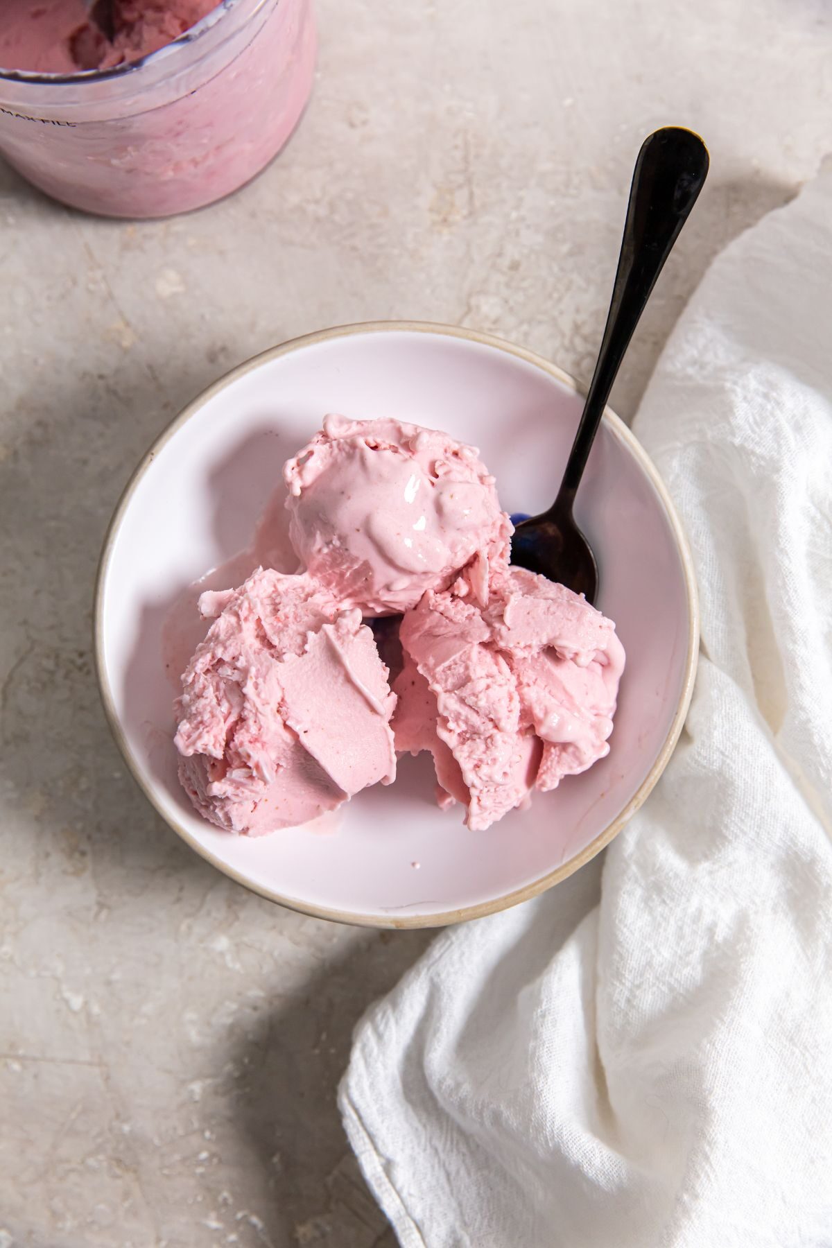 Ninja Creami Strawberry ice cream in a small white bowl with a black spoon