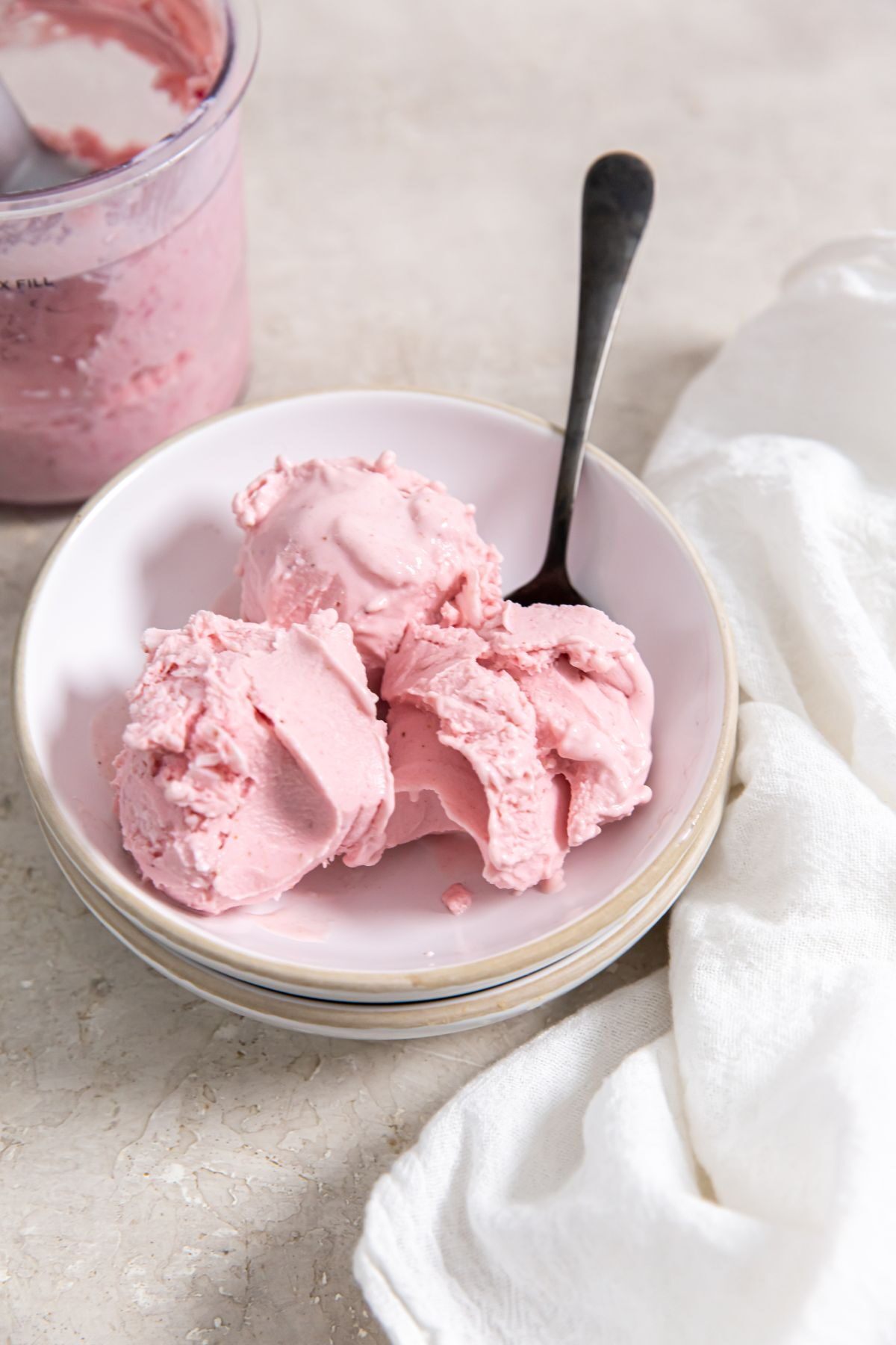 Ninja Creami Strawberry ice cream in a small white bowl with a black spoon