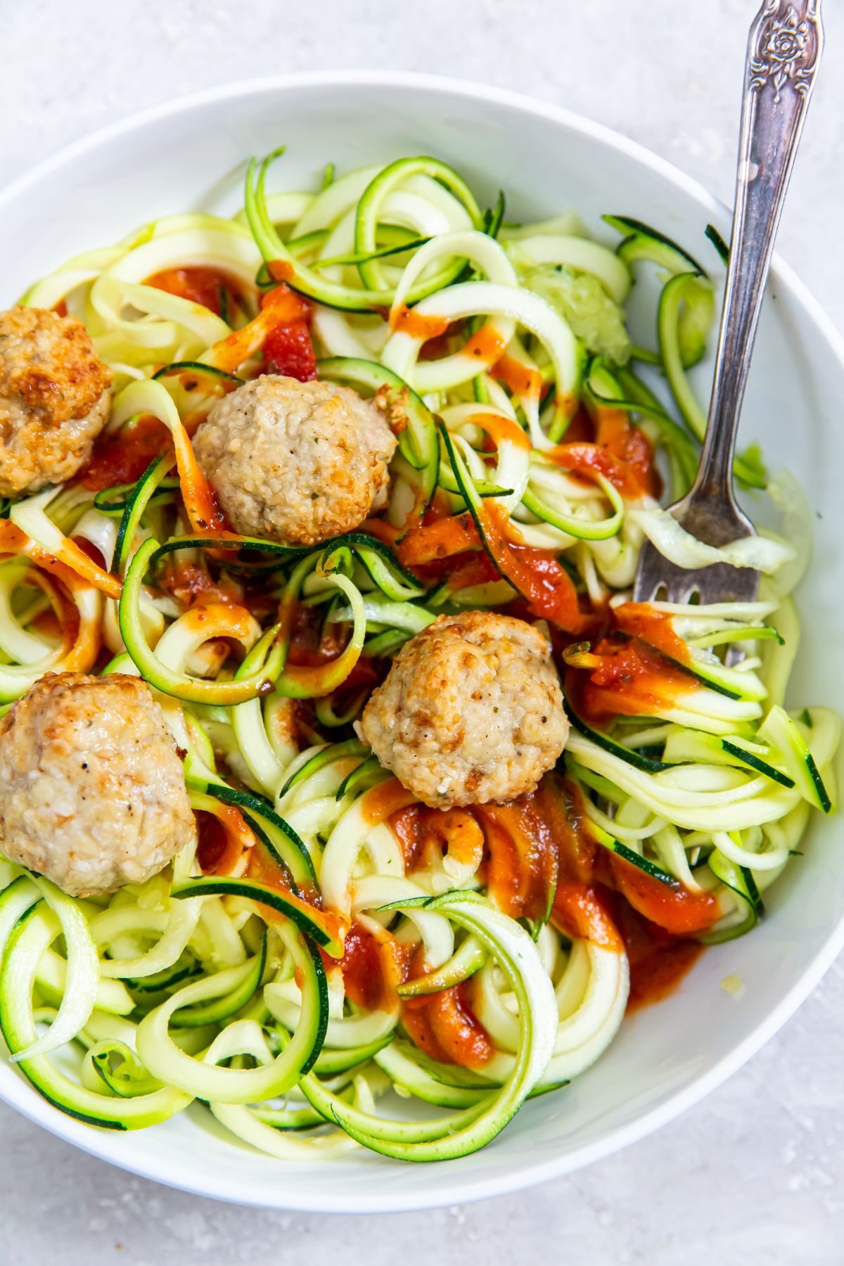 white bowl with zoodles turkey meatballs and spaghetti sauce inside
